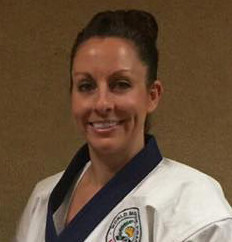 A smiling martial artist wearing a white uniform with a blue collar, posed against a neutral background.